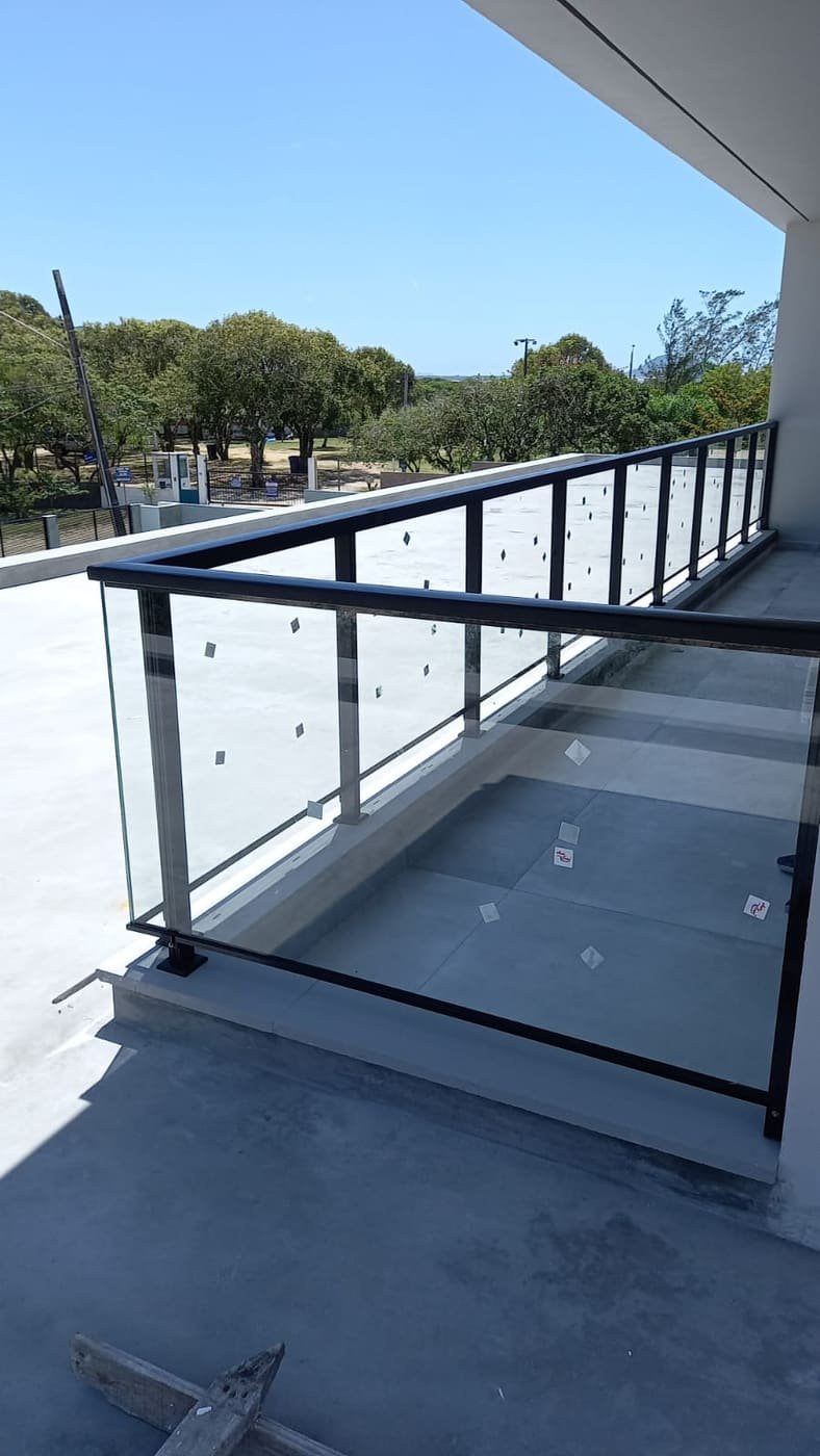 Guarda-corpo em vidro e alumínio preto com vista para a vegetação, instalado pela LM Vidros e Alumínios em Florianópolis